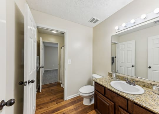 a bathroom with a sink and a toilet and a mirror at Grand Reserve Columbus in Columbus, GA