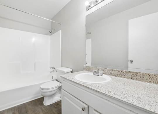 Second bathroom with a toilet, sink, and mirror in C2b floor plan at Riverwood Crossing apartments in Roswell, GA.