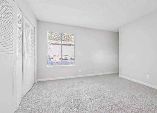 Second bedroom with a carpeted floor and a large window in B1 floor plan at Riverwood Crossing apartments in Roswell, GA.