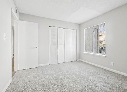 Second bedroom with carpeted floor and sliding doors closet on the side in B1 floor plan at Riverwood Crossing apartments in Roswell, GA..