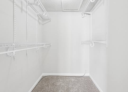 Master bedroom walk-in closet with a carpeted floor and white shelving in C2b floor plan at Riverwood Crossing apartments in Roswell, GA.