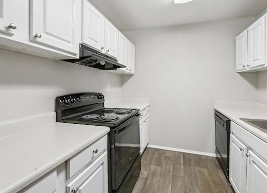 A kitchen with white cabinets and a black stove top oven in B1 floor plan at Riverwood Crossing apartments in Roswell, GA.