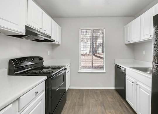 A kitchen with black appliances and white cabinets in C2b floor plan at Riverwood Crossing apartments in Roswell, GA.
