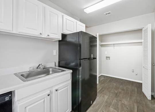 Kitchen with white cabinets and washer and dryer connections in C2b floor plan at Riverwood Crossing apartments in Roswell, GA.