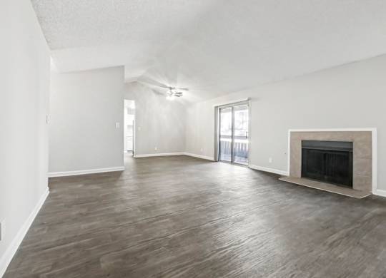 A spacious living room with a fireplace and sliding glass doors in C2b floor plan at Riverwood Crossing apartments in Roswell, GA..