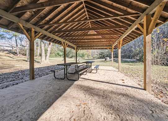 A wooden pavilion with a bench underneath it at Riverwood Crossing apartments in Roswell, GA.