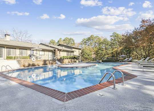 A swimming pool surrounded by a brick border and lounge chairs in autumn at Riverwood Crossing apartments in Roswell, GA.