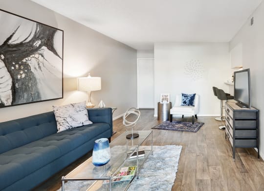 a living room with a blue couch and a glass coffee table