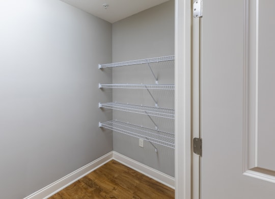 an empty closet in a home with white walls and a wood floor