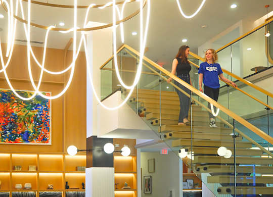 Two women are walking down a staircase at Era Apartments in Denton, TX