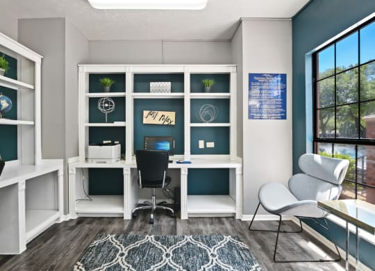 a home office with a large window and a blue accent wall