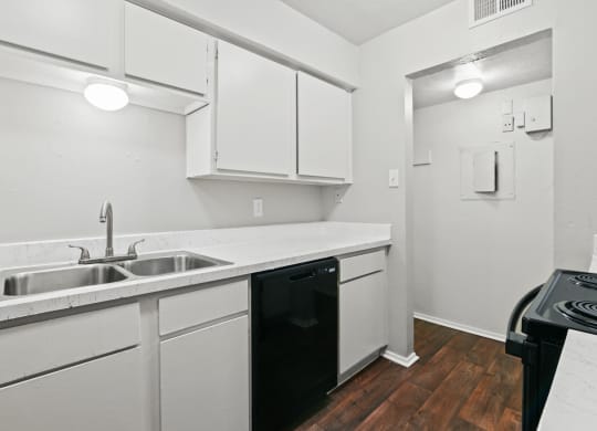 a kitchen with white cabinets and a black dishwasher