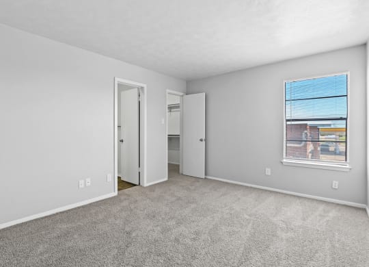 a bedroom with a large window and carpeted flooring
