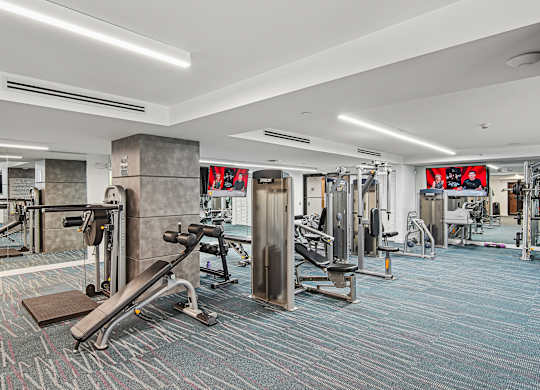 A fitness center with a variety of equipment including a bench press and a squat rack at Twenty2 West luxury apartments in Miami, FL