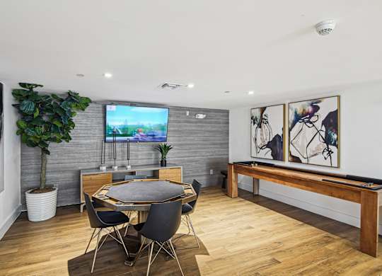 Resident gaming zone with a TV and a potted plant and shuffleboard at Twenty2 West luxury apartments in Miami, FL