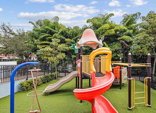 A playground with a red slide and a yellow and green play structure at Twenty2 West luxury apartments in Miami, FL