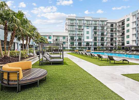 A modern outdoor seating area with a pool and palm trees at Twenty2 West luxury apartments in Miami, FL