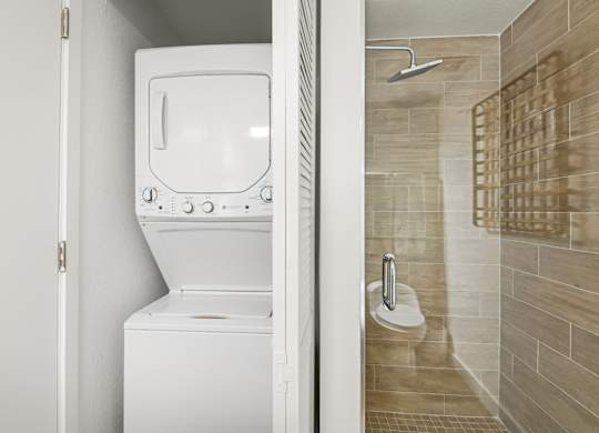 Studio Sixty2 floor plan bathroom with a tiled walk-in shower and stacked washer and dryer at Twenty2 West luxury apartments in Miami, FL