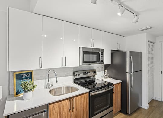 Studio Sixty2 kitchen with white cabinets and stainless steel appliances at Twenty2 West luxury apartments in Miami, FL