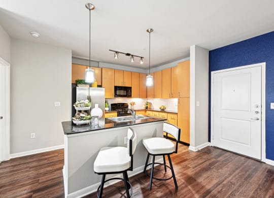 Open-concept kitchen with granite countertops and stainless steel appliances at The Grand at Upper Kirby apartments in Houston, TX