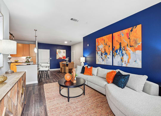 Spacious living room with blue accent wall and contemporary furniture at The Grand at Upper Kirby apartments in Houston, TX