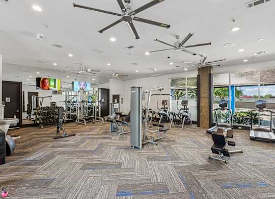 A gym with a variety of equipment including treadmills, weights, and exercise machines.