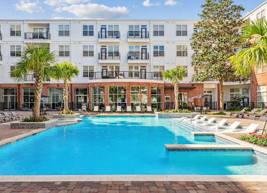 A large swimming pool in front of a multi-story apartment building.