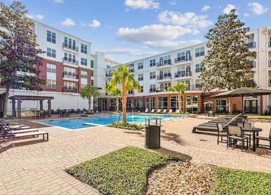 A large outdoor pool area with a patio and lounge chairs at The Grand At Upper Kirby in Houston, TX