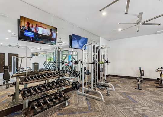 A gym with a variety of equipment including a flat screen TV.