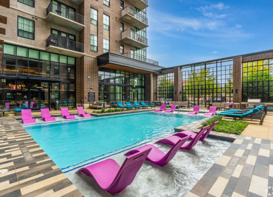 Our resort-style swimming pool with pink in-pool lounge chairs at The Case apartments in Dallas, TX