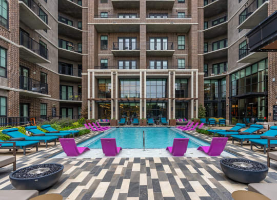 Our sparkling pool with blue loungers and pink in-pool lounge chairs at The Case apartments in Dallas, TX