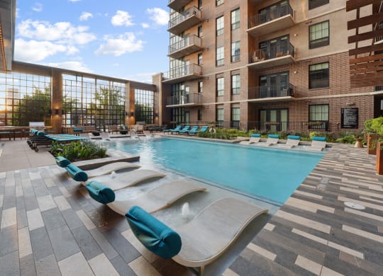 an outdoor pool with lounge chairs at the bradley braddock road station apartments