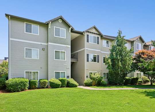 Apartment building with green bushes in front.
