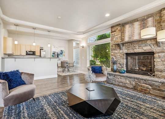 Clubhouse with a stone fireplace, kitchen, and seating at The Madison apartments in Olympia, WA