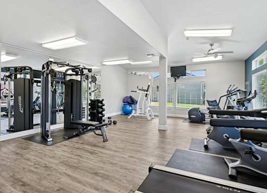 A spacious gym with a variety of equipment including treadmills, weights, and exercise machines at The Madison apartments in Olympia, WA