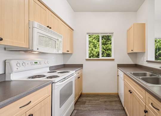 A kitchen with white appliances and wooden cabinets at The Madison Apartments in Olympia, WA