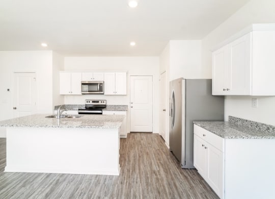 a kitchen with white cabinets and granite countertops at Beacon at Meridian, San Antonio Texas