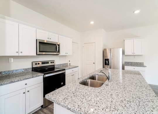 a kitchen with white cabinets and granite countertops at Beacon at Meridian, San Antonio, 78245