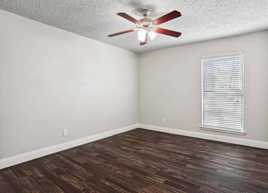 Upgraded A1 bedroom with a ceiling fan and a window with blinds at Vine Apartments in Arlington, TX