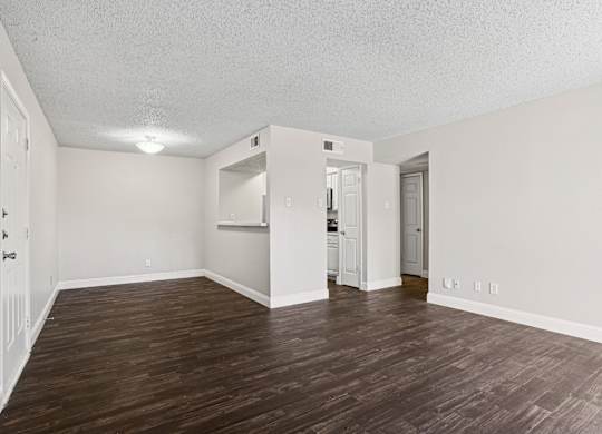 Upgraded A1 living room with wooden floors and white walls at Vine Apartments in Arlington, TX