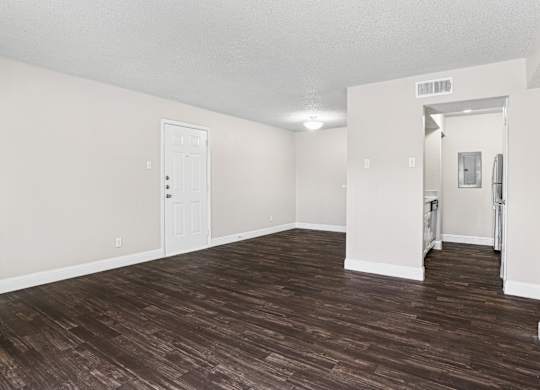 Upgraded A1 living room with a wooden floor and white walls at Vine Apartments in Arlington, TX