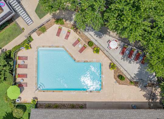 An aerial view of a swimming pool surrounded by trees and a parking lot at Vine Apartments in Arlington, TX
