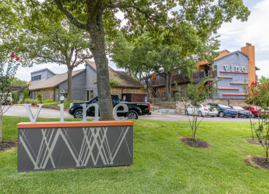 A sign for Vine apartments surrounded by grass at Vine Apartments in Arlington, TX