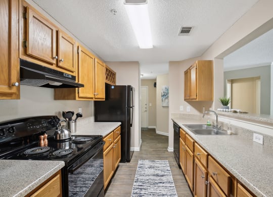 Model apartment kitchen with wood cabinets and black appliances at Wellington Ridge in Lawrenceville, GA