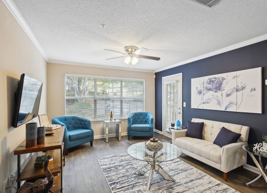 a living room with blue and white furniture and a ceiling fan at Wellington Ridge in Lawrenceville, GA