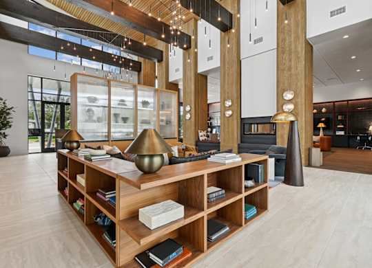 Leasing office lounge area with bookshelves wrapping around the couch at Whispering Pines at Westdale Hills in Euless, TX