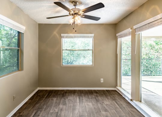 an empty living room with a ceiling fan and a window