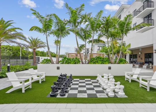 a large chess board is set up on a lawn in front of a building at Westgate on University in Lauderhill, FL