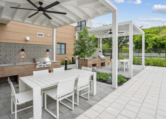 a patio with a white table and chairs and a grill at Westgate on Univeristy in Lauderhill, FL