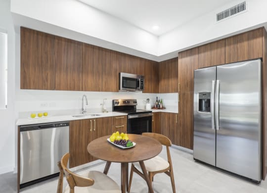 Kitchen with stainless steel appliances and a wooden table in A2 Floor Plan at Westgate on University in Lauderhill, FL